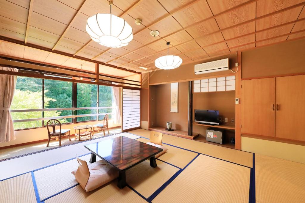 un salon avec une table et une grande fenêtre dans l'établissement 秘境のおやど 龍峡亭　HIKYOUNOOYADO RYUKYOUTEI, à Tokimata