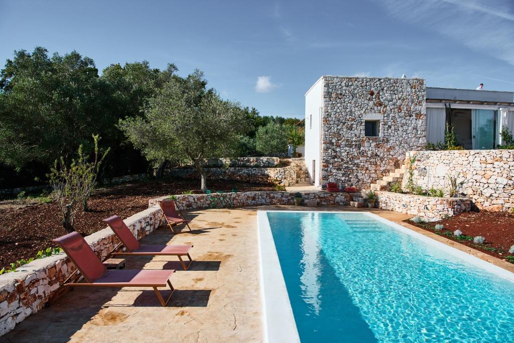 une piscine avec des chaises et une maison dans l'établissement La Selvaggia Ostuni - w pool, à Ostuni