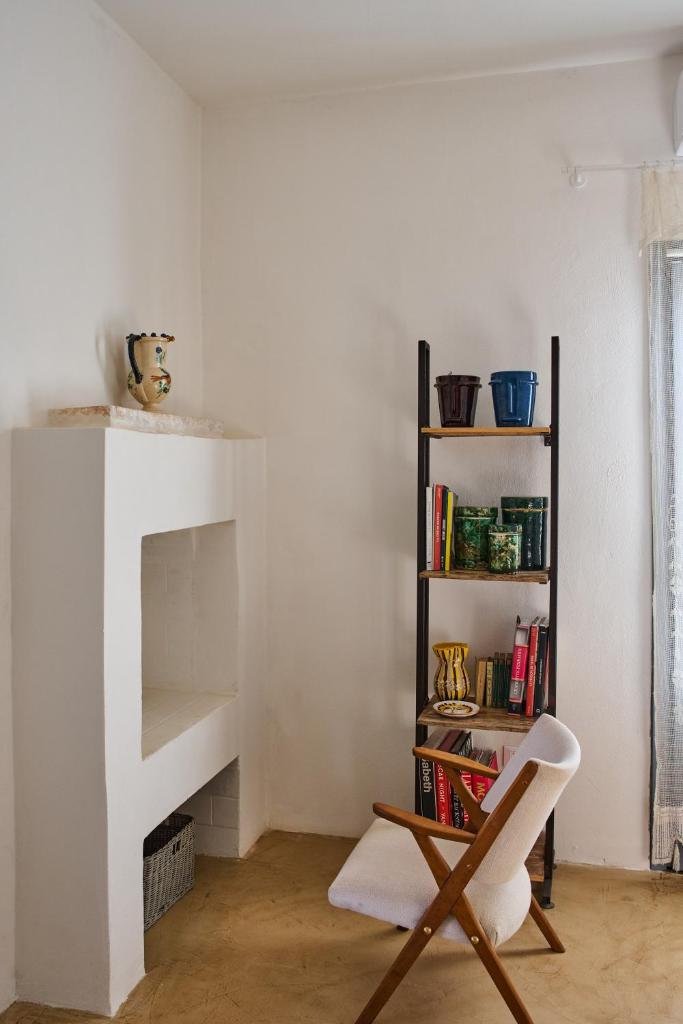 Cette chambre blanche dispose d'une chaise et d'une étagère. dans l'établissement La Selvaggia Ostuni - w pool, à Ostuni