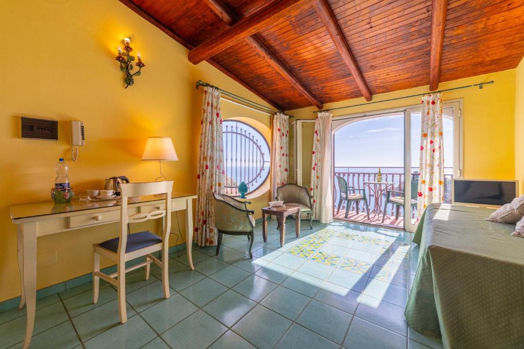 une chambre avec un lit et un bureau et un balcon dans l'établissement Mendolia Beach Hotel, à Taormine