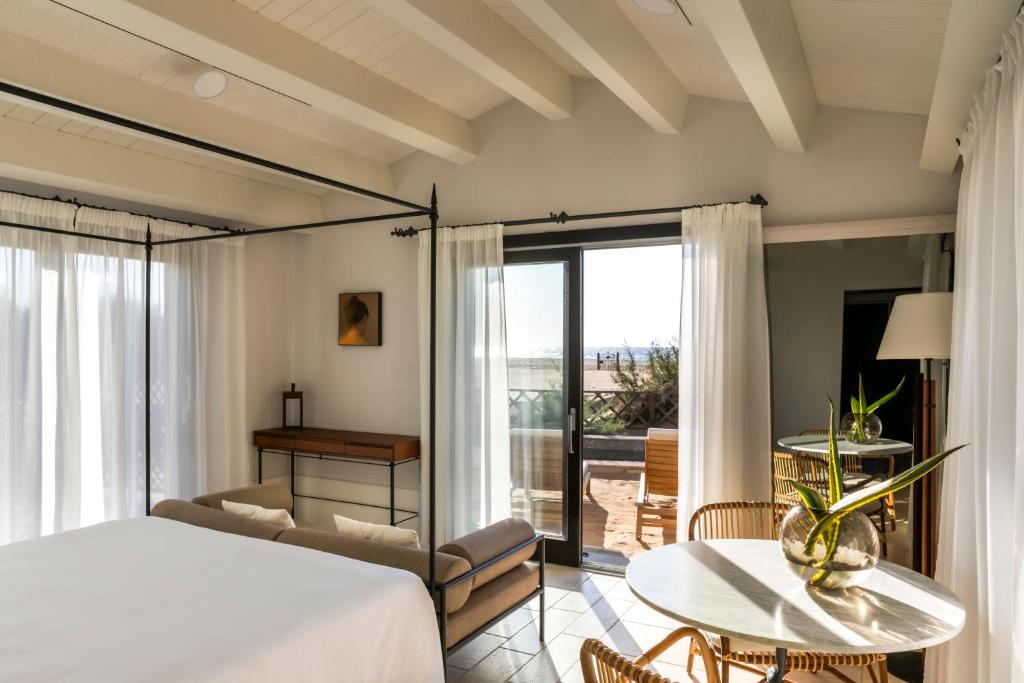 - une chambre avec un lit, une table et un balcon dans l'établissement Hotel Le Dune Piscinas, à Ingurtosu