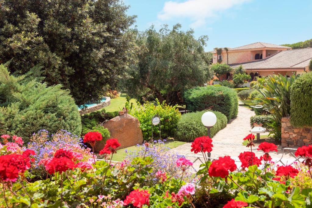 un jardin avec des fleurs et des buissons rouges dans l'établissement Hotel Baia di Nora, à Pula