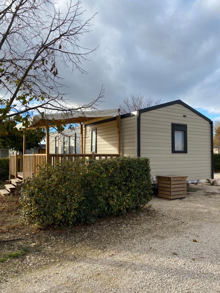 une petite maison blanche avec une clôture devant elle dans l'établissement Camping L' Arlesienne, à Arles