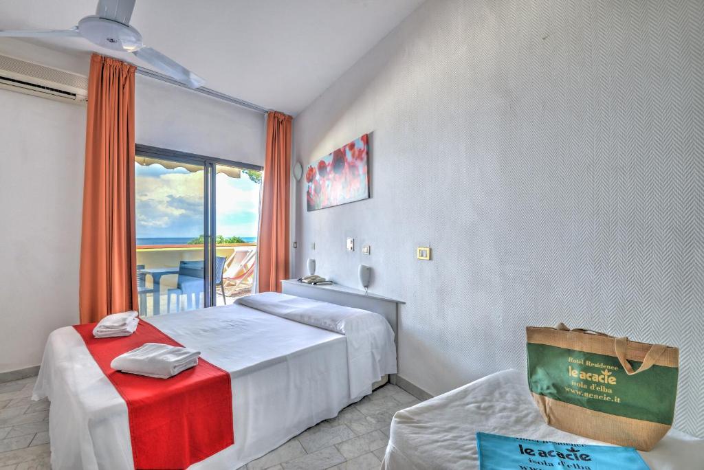 une chambre d'hôtel avec deux lits et une fenêtre dans l'établissement Residence Le Acacie, à Capoliveri