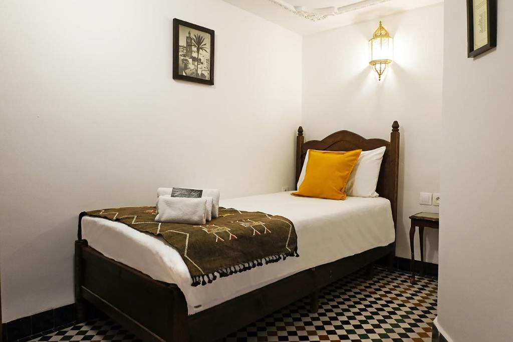 une chambre avec un lit avec des oreillers orange et blancs dans l'établissement Riad Alassala Fes, à Fès