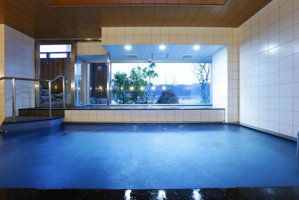 - une piscine avec un sol bleu et une fenêtre dans l'établissement Okukinosaki Seaside Hotel, à Toyooka