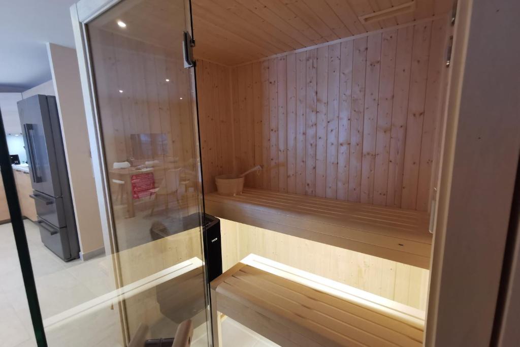 un sauna avec des murs en bois et une porte en verre dans l'établissement L'écrin des neiges - Sauna, à La Féclaz