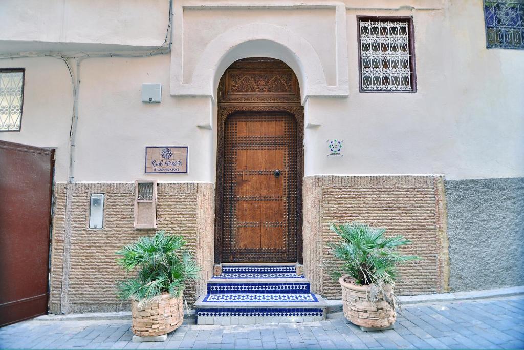 un bâtiment avec une porte en bois et deux plantes en pot dans l'établissement Riad Alassala Fes, à Fès