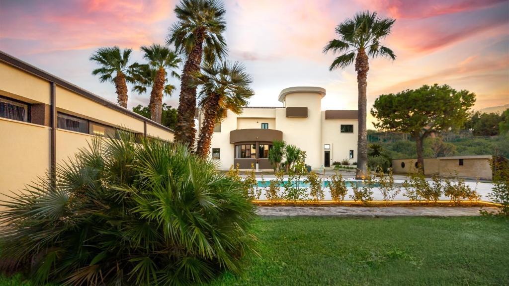un bâtiment avec des palmiers en face d'une cour dans l'établissement La Gigasuite - Design Villa at Sea with Spa & Pool, à Tarente