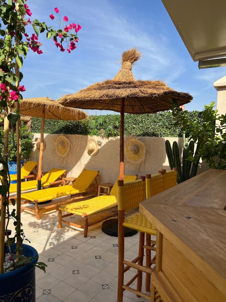 un groupe de chaises et un parasol sur une terrasse dans l'établissement Riad Les Gazelles D'Orient Marrakech, à Marrakech
