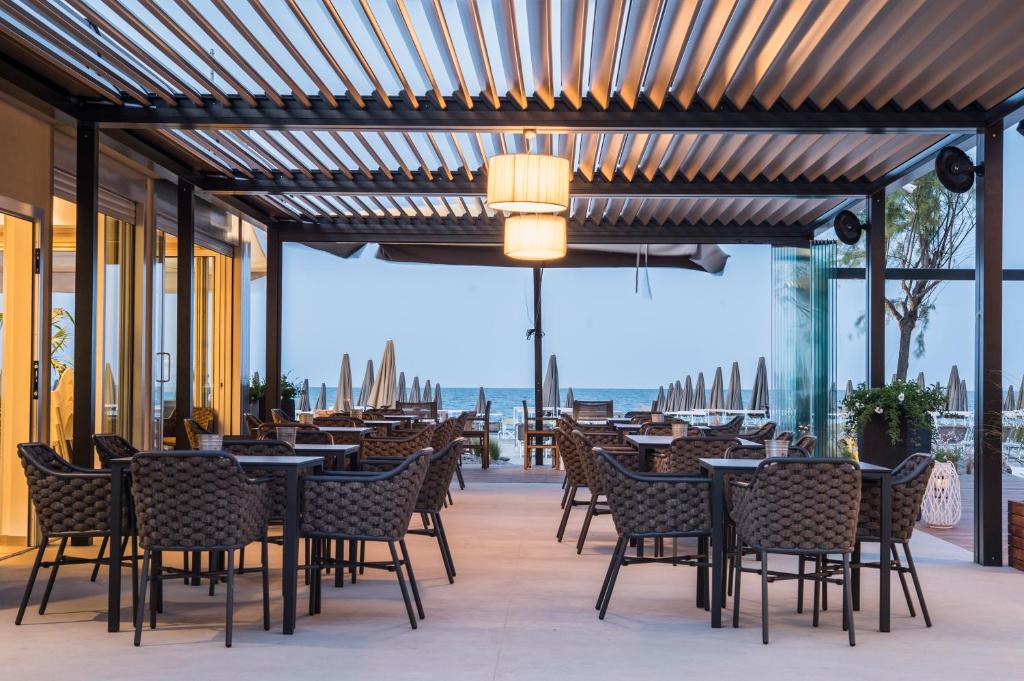un restaurant avec des tables et des chaises et une vue sur l'océan dans l'établissement Hotel Solemare, à Milano Marittima
