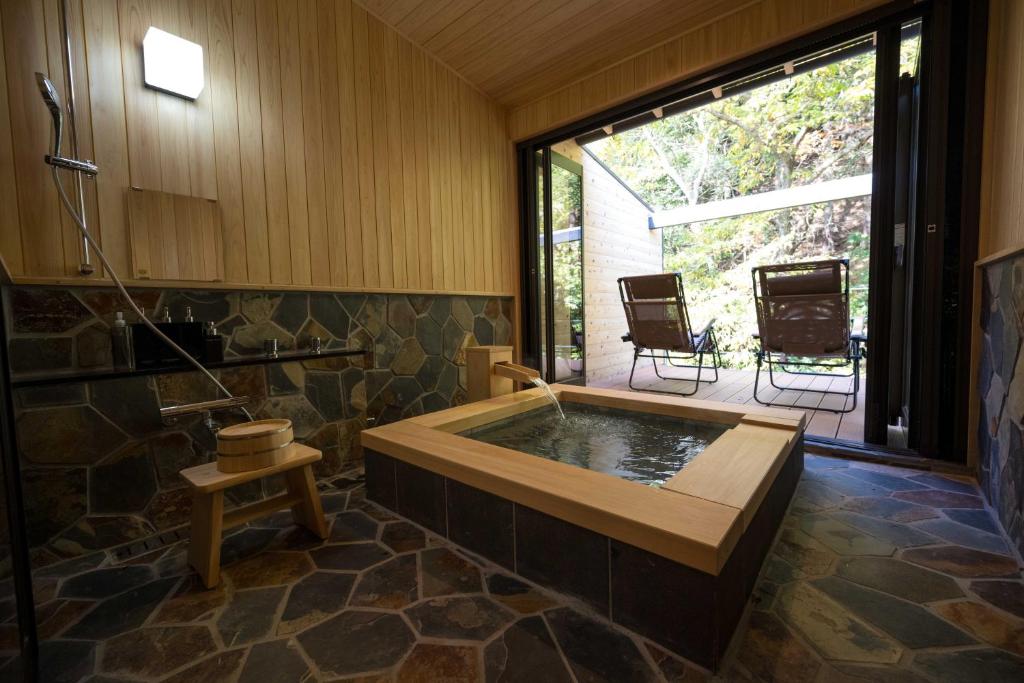 une baignoire jacuzzi dans une chambre avec patio dans l'établissement 横川温泉湯殿ととのゆ, à Shimoda