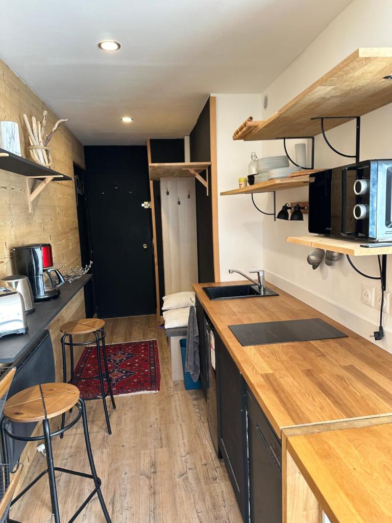 - une cuisine avec un comptoir et quelques tabourets dans l'établissement SKI AUX PIEDS, à Vars