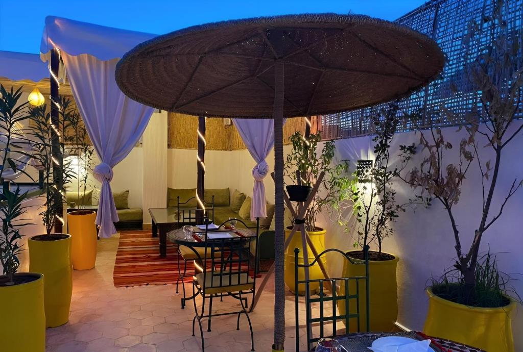 un patio avec tables, chaises et un parasol dans l'établissement Riad Iklil, à Marrakech