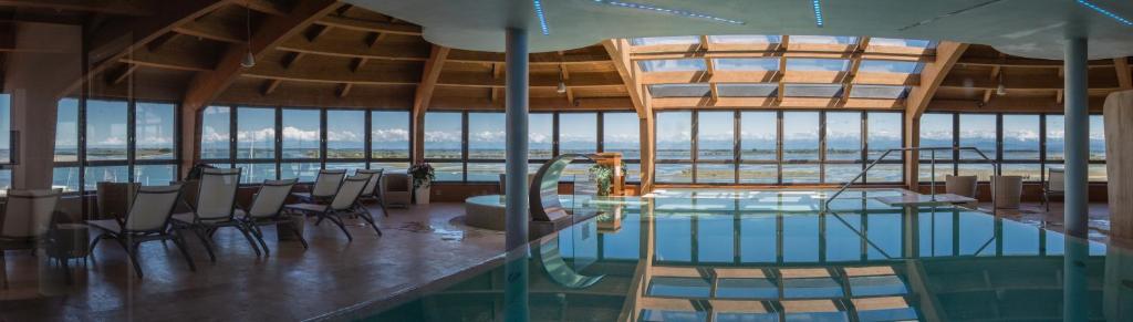 - une piscine dans un bâtiment avec des chaises et une table dans l'établissement Laguna Palace Hotel Grado, à Grado