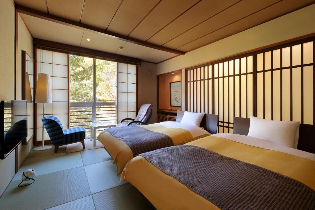 une chambre d'hôtel avec deux lits et une fenêtre dans l'établissement Yamayuri no Yado, à Hanamaki