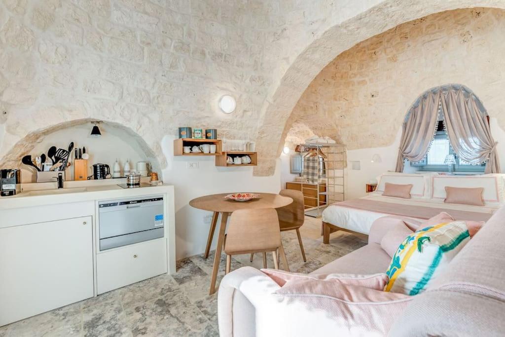 Cet appartement comprend une chambre avec deux lits et une cuisine avec une table. dans l'établissement Trullo Under The Apulian Sky By Raro Villas, à Martina Franca