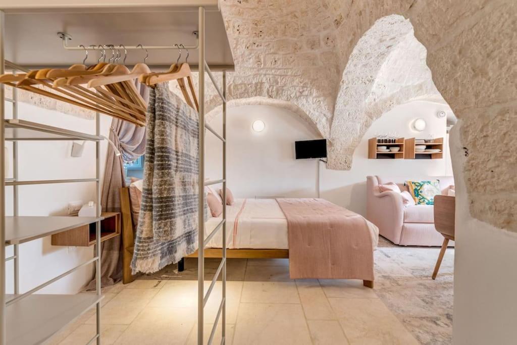- une chambre avec un lit dans une pièce dotée d'un mur en pierre dans l'établissement Trullo Under The Apulian Sky By Raro Villas, à Martina Franca