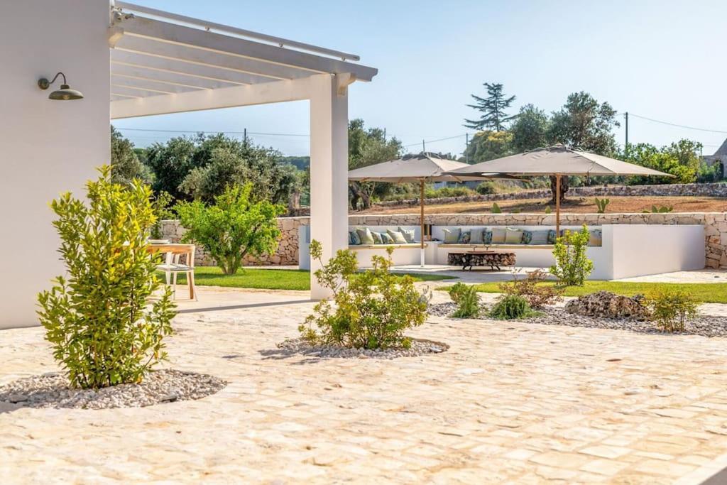 - une terrasse avec des parasols, une table et des chaises dans l'établissement Trullo Under The Apulian Sky By Raro Villas, à Martina Franca