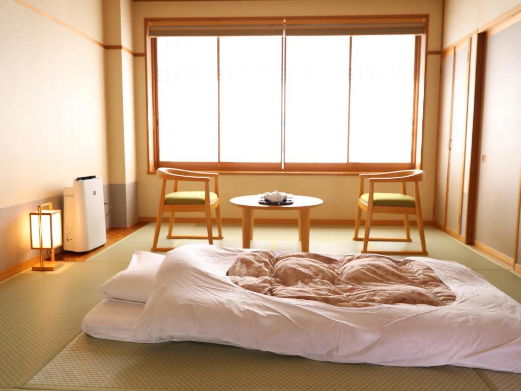 Ce lit se trouve dans une chambre avec 2 chaises et une table. dans l'établissement Hotel Asafuji, à Fujikawaguchiko 37 autres photos