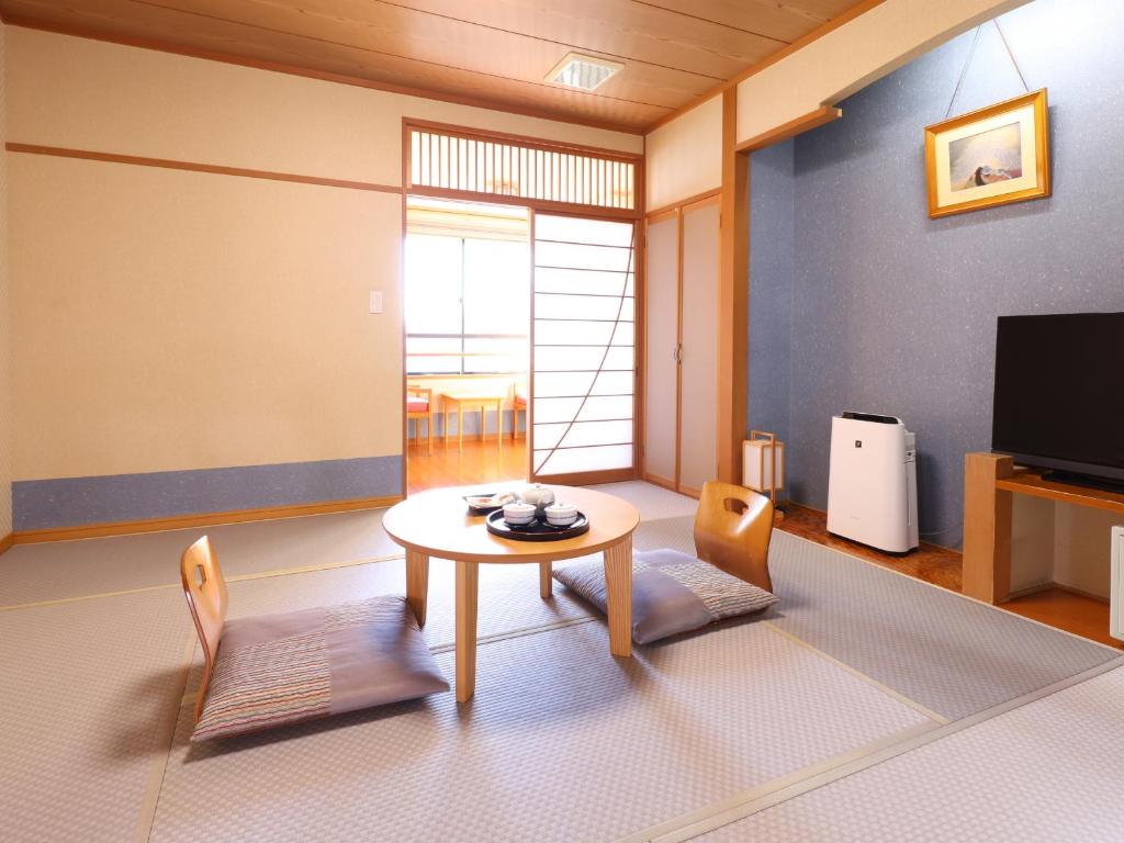 - un salon avec une table, des chaises et une télévision dans l'établissement Hotel Asafuji, à Fujikawaguchiko