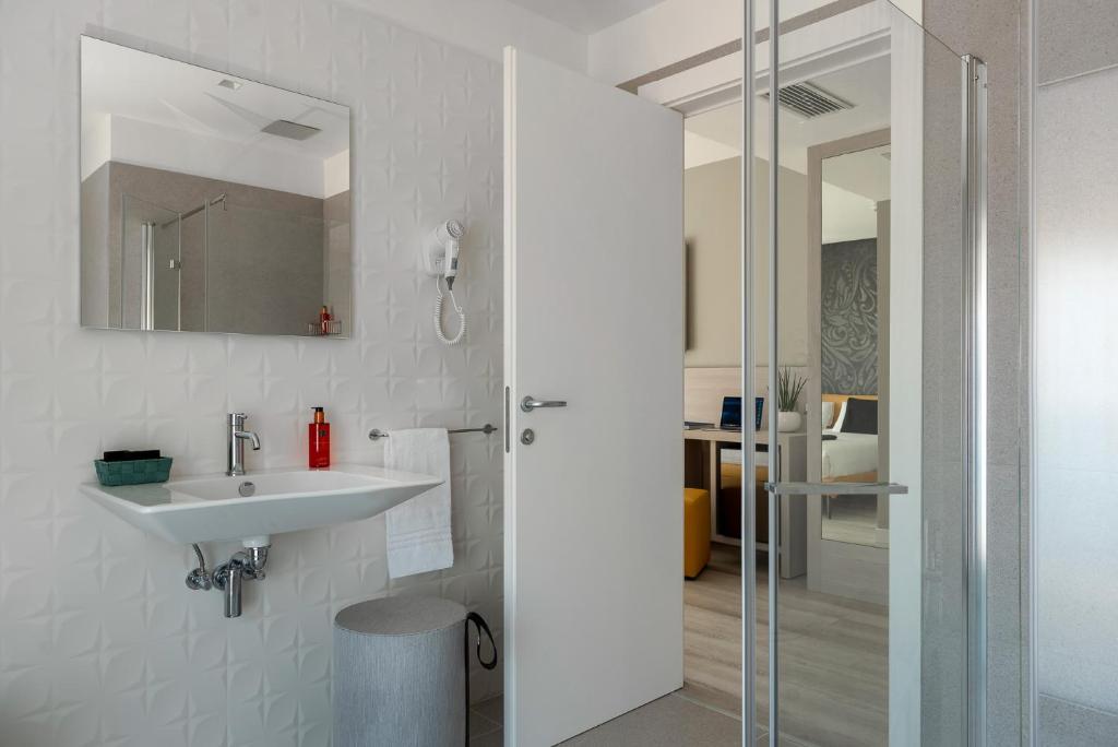 une salle de bain blanche avec lavabo et douche dans l'établissement Hotel Delle Rose, à Lido di Jesolo