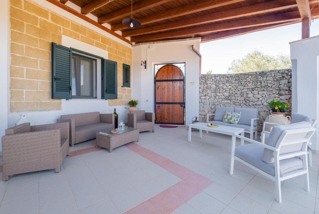 une terrasse avec des canapés et des chaises ainsi qu'une porte en bois dans l'établissement Villa VentoSolare Luxury - Specchia, à Specchia