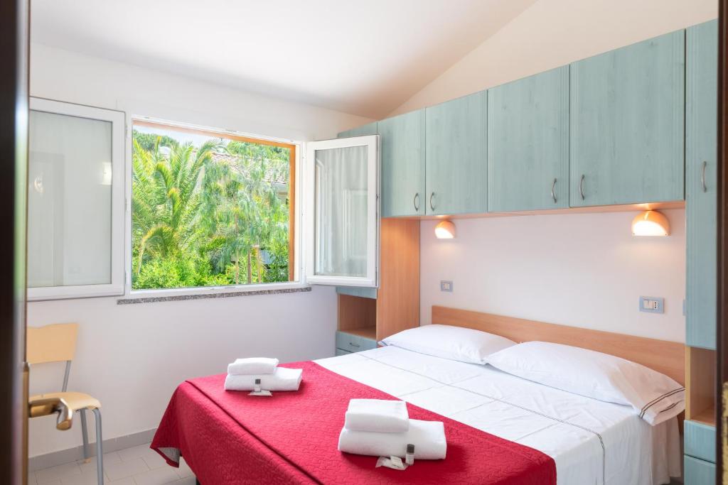 une chambre avec un lit avec une couverture rouge et une fenêtre dans l'établissement Golfo di Maremma Village, à Albinia