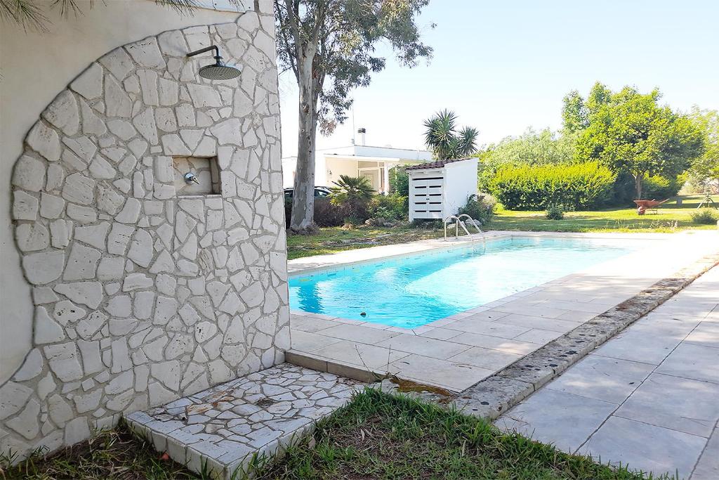 - une piscine avec un mur en pierre à côté d'une maison dans l'établissement La Dimora dei Gelsi, à Castri di Lecce
