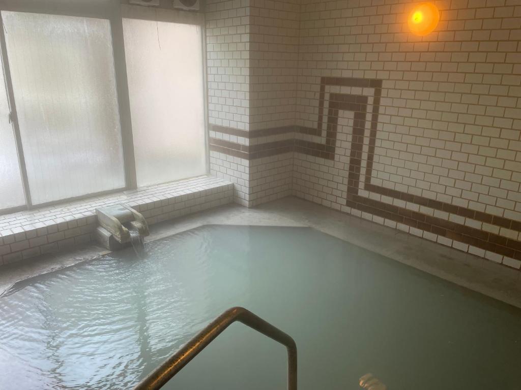 d'une salle de bains pourvue d'une baignoire jacuzzi à côté d'une fenêtre. dans l'établissement adex Inn, à Noboribetsu