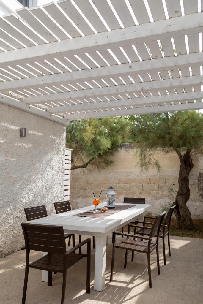 une table blanche et des chaises sous une pergola blanche dans l'établissement Lido degli Angeli Case Vacanza-Beach, à Punta Prosciutto