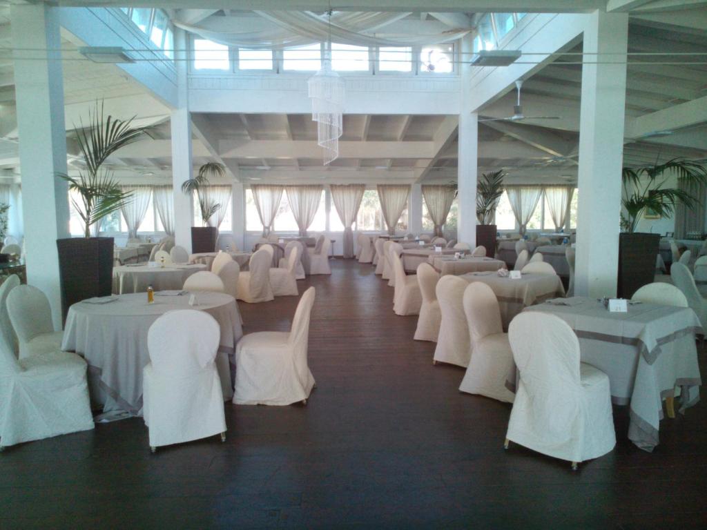 une salle de banquet avec des tables blanches et des chaises blanches dans l'établissement Valtur Baia del Gusmay Beach Resort, à Peschici 79 autres photos
