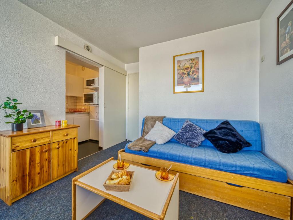 un salon avec un canapé bleu et une table dans l'établissement Apartment Lunik Orion-41 by Interhome, au Corbier