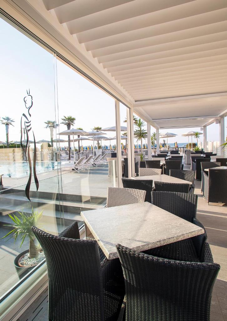 un restaurant avec une table et des chaises et une piscine dans l'établissement Hotel Sayonara, à Lido di Jesolo