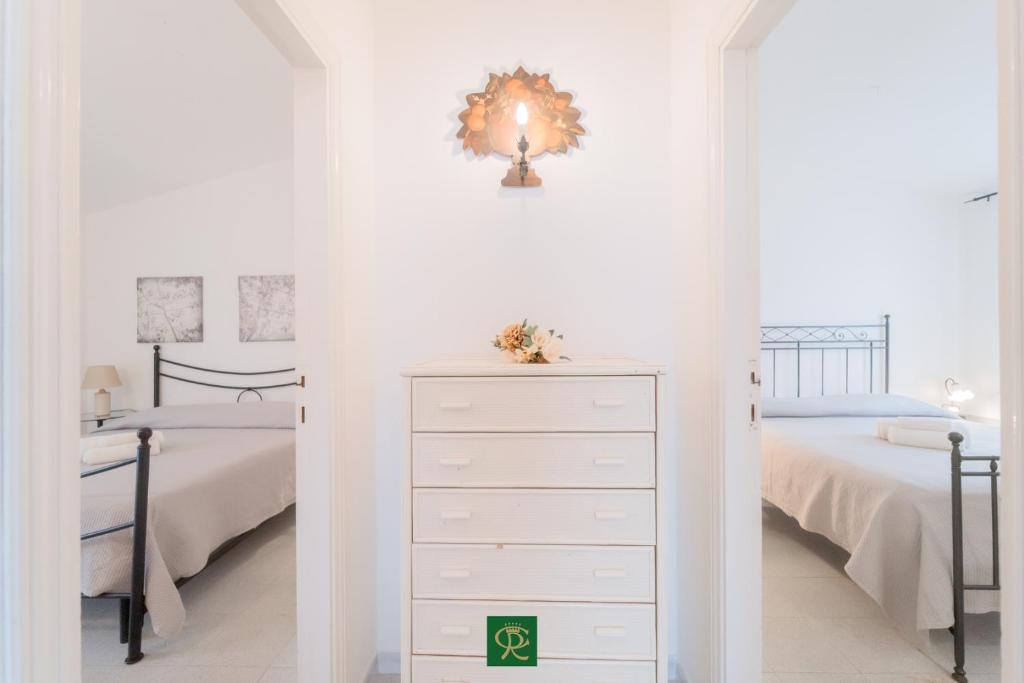 - une chambre blanche avec 2 lits et une commode dans l'établissement Albatros, à Capoliveri