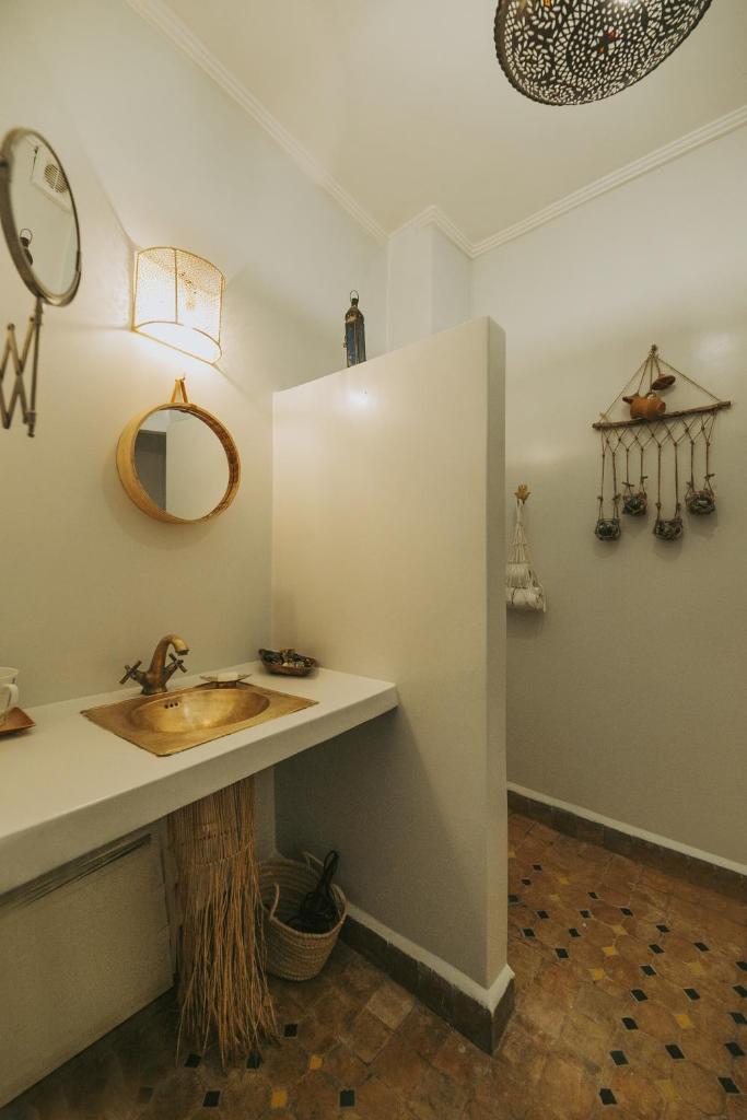 une salle de bain avec un lavabo et un miroir au mur dans l'établissement Riad Dar Coram, à Marrakech