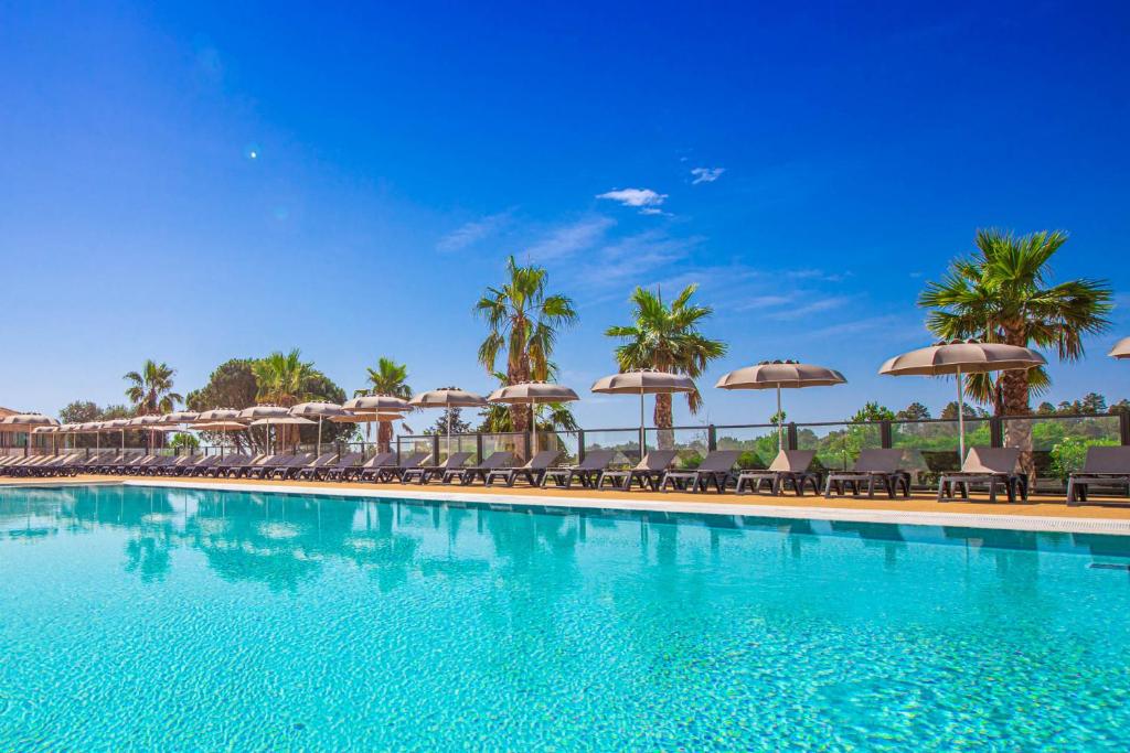 une piscine avec chaises et parasols dans l'établissement Mobil Home Golf de Saint Tropez, à La Garde-Freinet