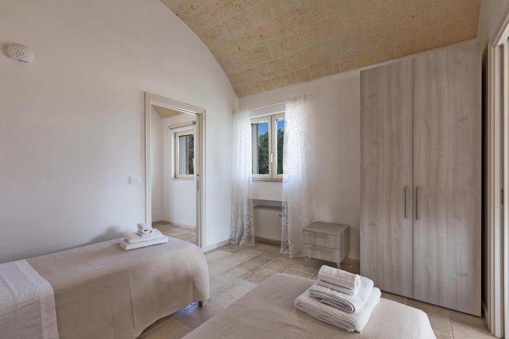 une chambre blanche avec deux lits et une fenêtre dans l'établissement Villa Angi by Perle di Puglia, à San Vito dei Normanni