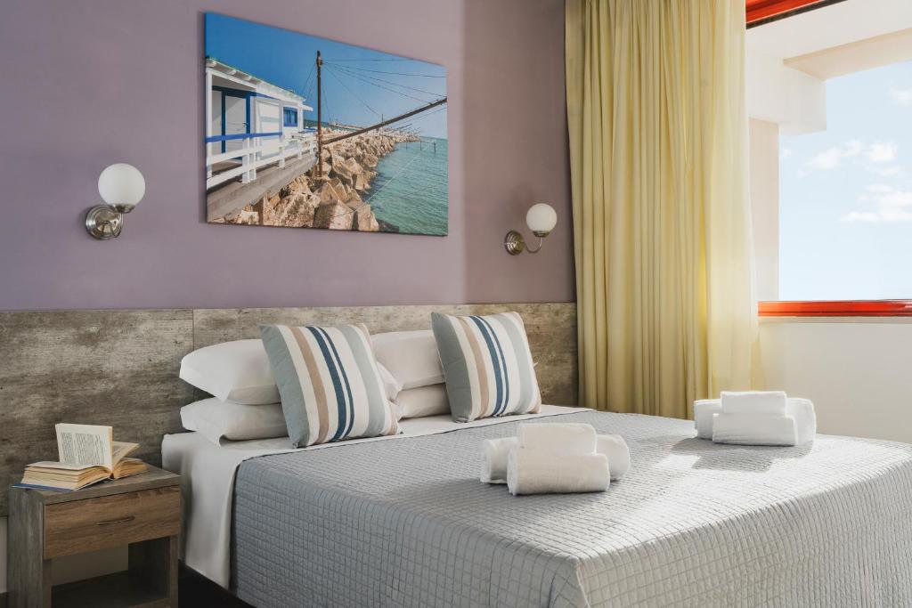 - une chambre avec un lit blanc et une vue sur l'océan dans l'établissement Hotel Club La Villa, à Martinsicuro