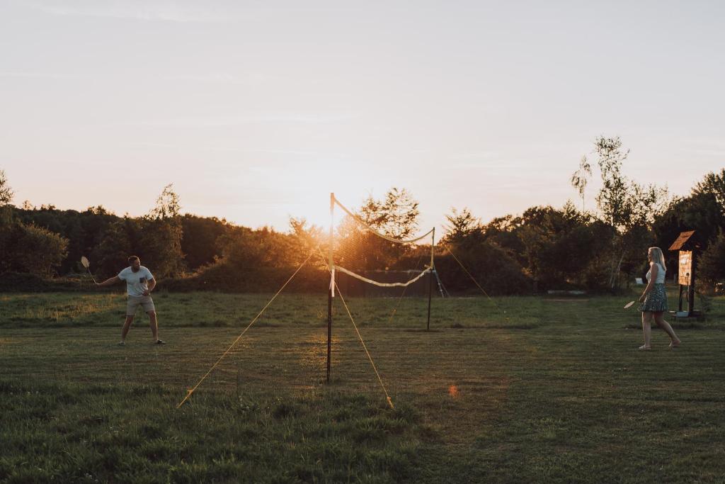 deux personnes jouant avec un cerf-volant dans un champ dans l'établissement Charmecamping Domaine Bleu Celeste, à Couleuvre