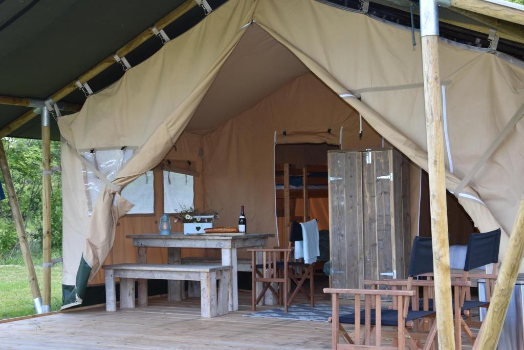 une tente avec des tables et des chaises en bois. dans l'établissement Charmecamping Domaine Bleu Celeste, à Couleuvre