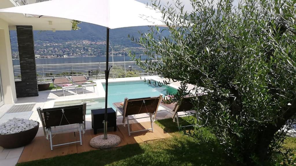 une piscine avec des chaises et un parasol dans l'établissement Villa Mimosa Bellagio Wild Flowers, à Oliveto Lario