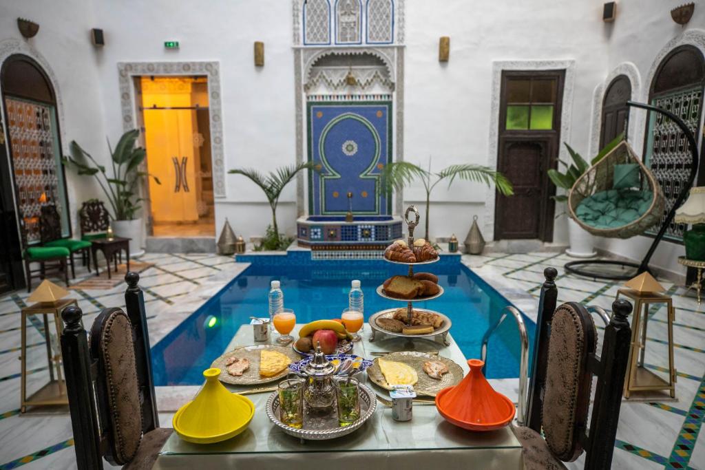 - une table avec de la nourriture devant la piscine dans l'établissement Palais Chahd Luxury, à Fès