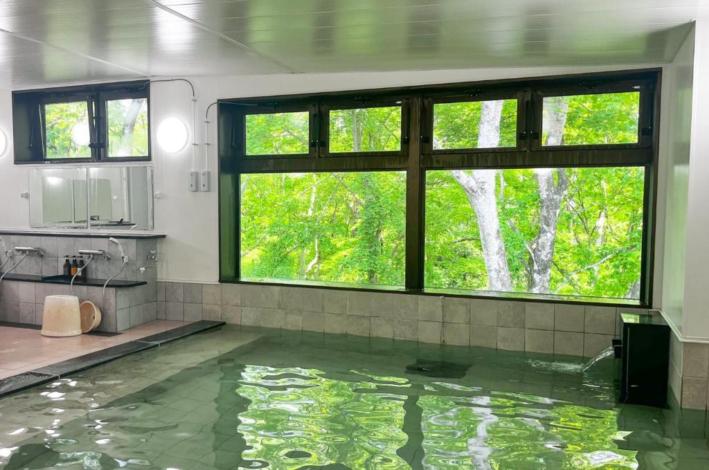 La salle de bains est pourvue d'une grande piscine d'eau et d'une fenêtre. dans l'établissement Shizukatei, à Hiraizumi