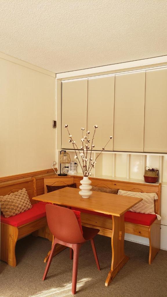 une table de salle à manger avec un vase de fleurs dessus dans l'établissement Balcon plein Sud sur les pistes, à Isola 2000