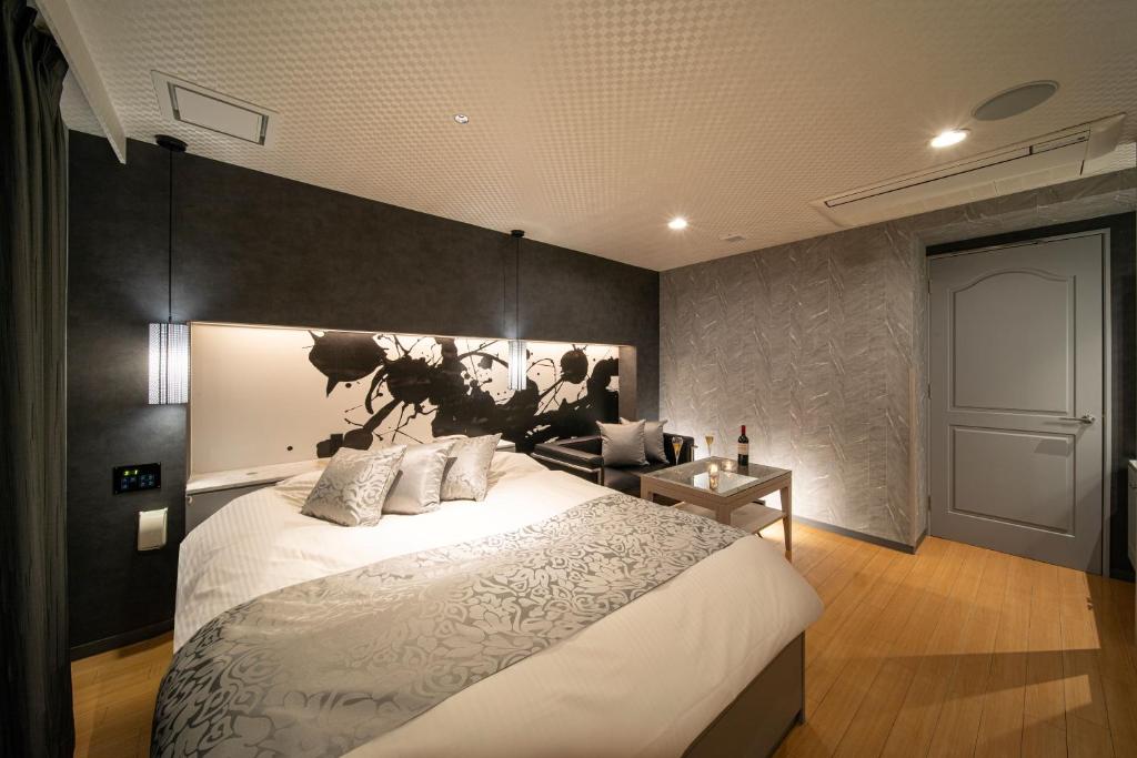 une chambre avec un grand lit et un canapé dans l'établissement ホテル継kei男塾ホテルグループ, à Himeji