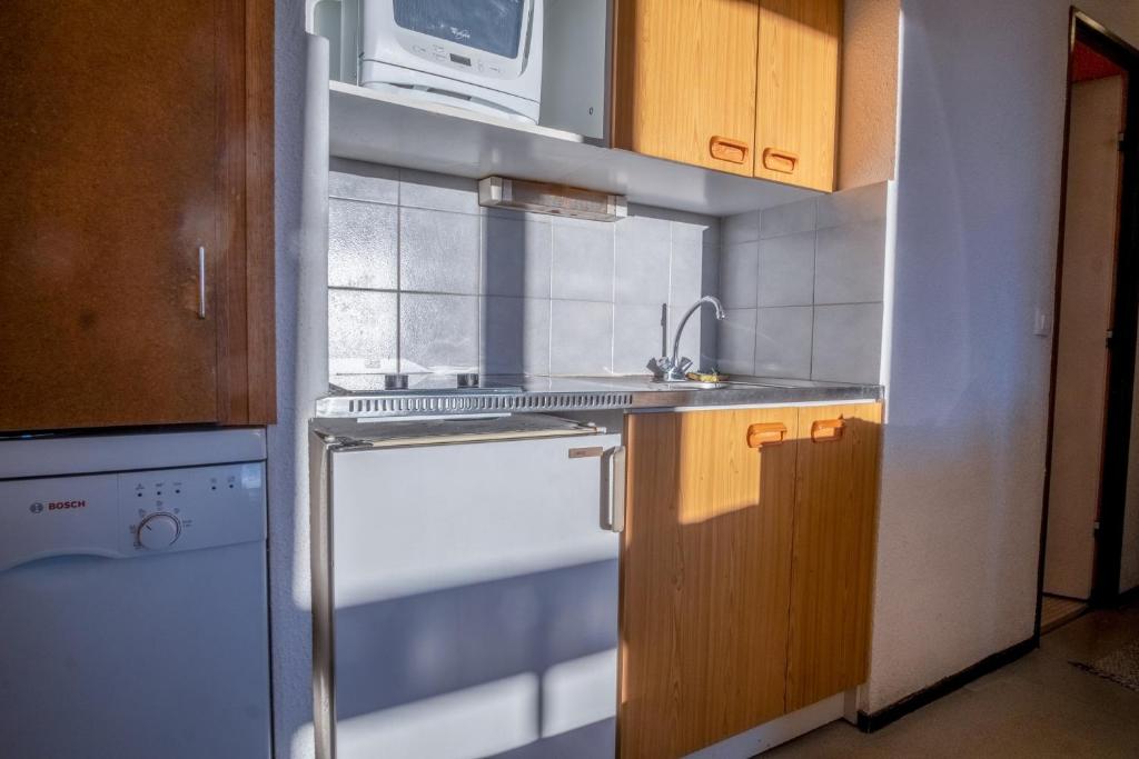 une cuisine avec une cuisinière, un évier et un micro-ondes dans l'établissement Appartement Aldeïa - Welkeys, à Huez