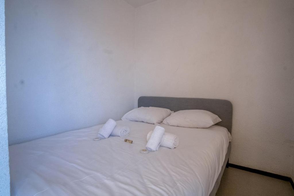 un lit avec des oreillers blancs et des serviettes dessus dans l'établissement Appartement Aldeïa - Welkeys, à Huez