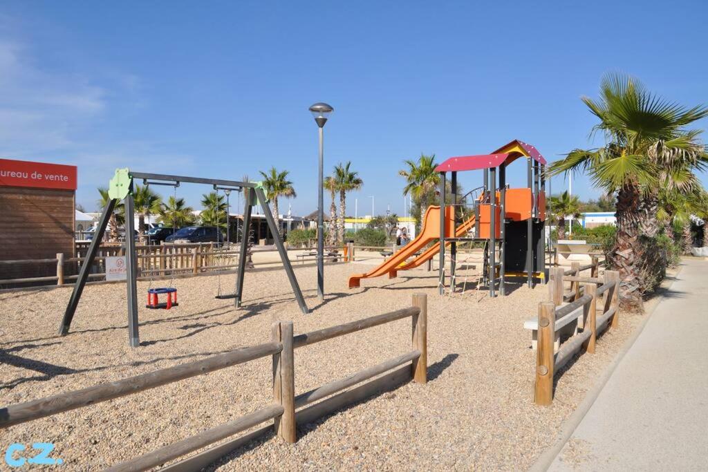 - une aire de jeux avec des toboggans et une balançoire dans l'établissement Mobile-home les pieds dans l'eau, à Palavas-les-Flots