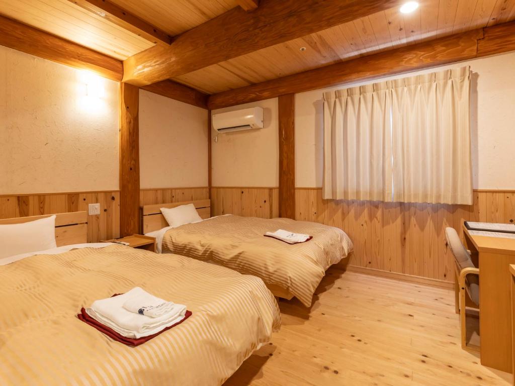 Cette chambre comprend deux lits et un bureau. dans l'établissement Tennenonsen Harunonoyu, à Kōchi